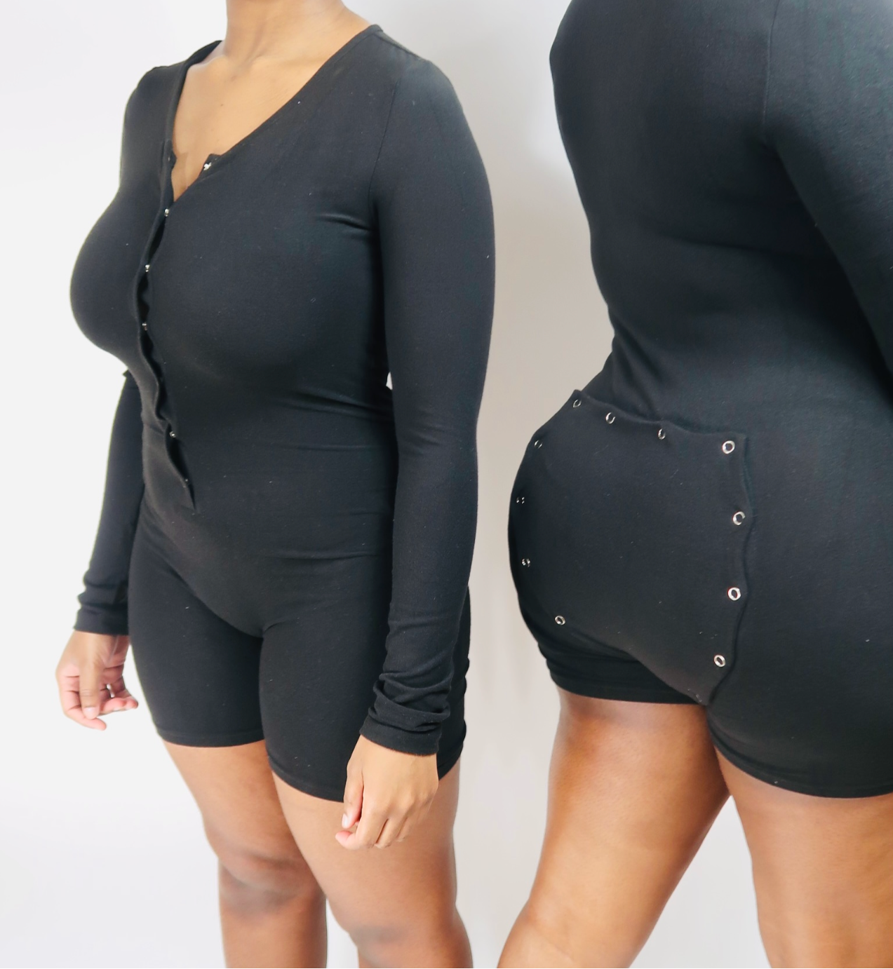A black long-sleeve cotton romper with a low neckline and high-cut leg design, featuring a central front button fastening and a butt-flap.